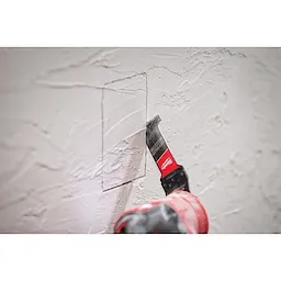 Worker using the NITRUS CARBIDE Extreme Materials Universal Fit OPEN-LOK Multi-Tool Blade to cut through plaster