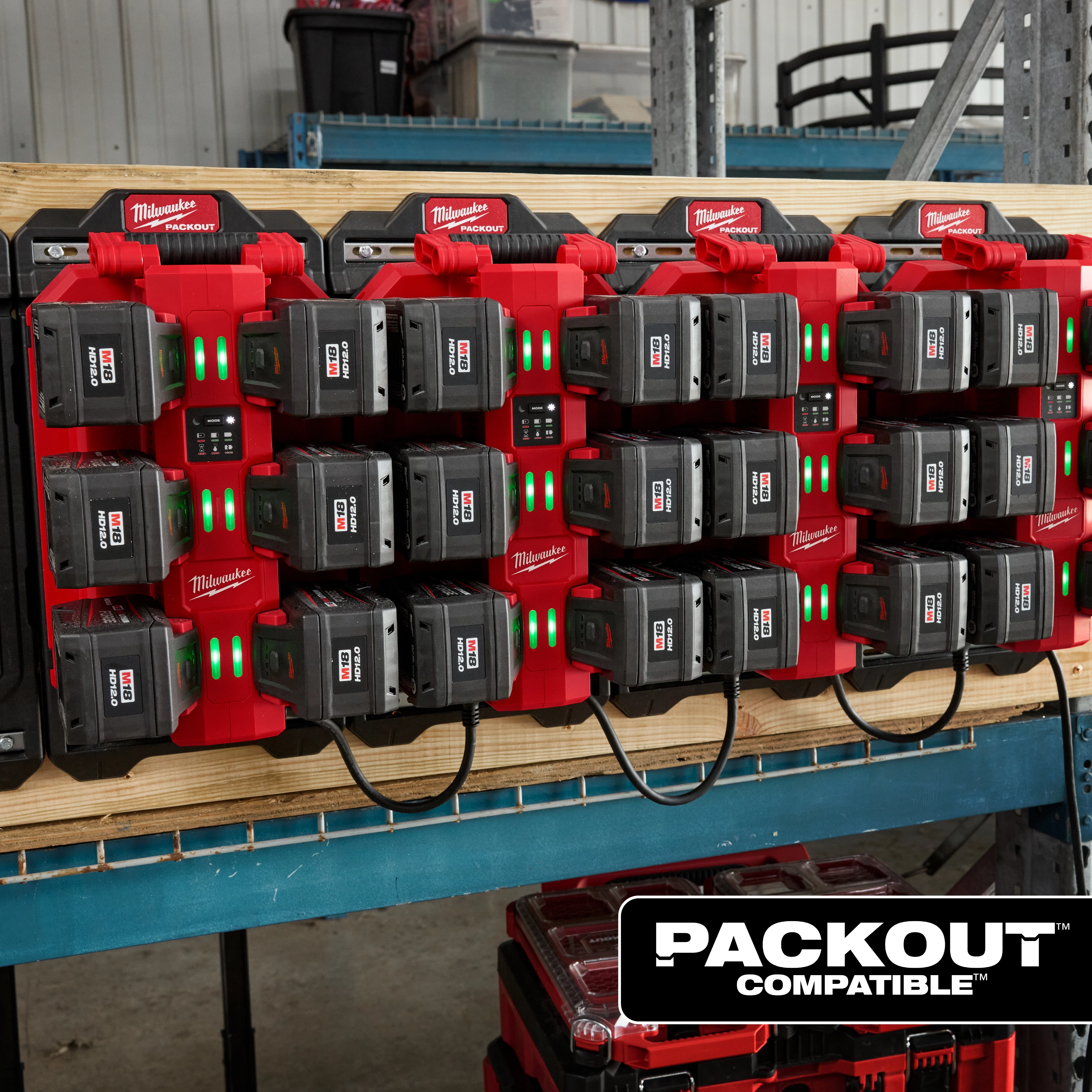 The image shows an M18™ Six Bay Daisy Chain Rapid Charger mounted on a wooden surface. The charger is holding multiple battery packs with green indicator lights illuminated. The charger setup is labeled "PACKOUT™ COMPATIBLE" at the bottom right of the image.