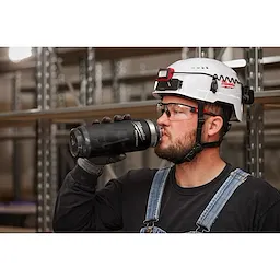 Image of a worker drinking from a Milwaukee PACKOUT Insulated Bottle with Chug Lid in black