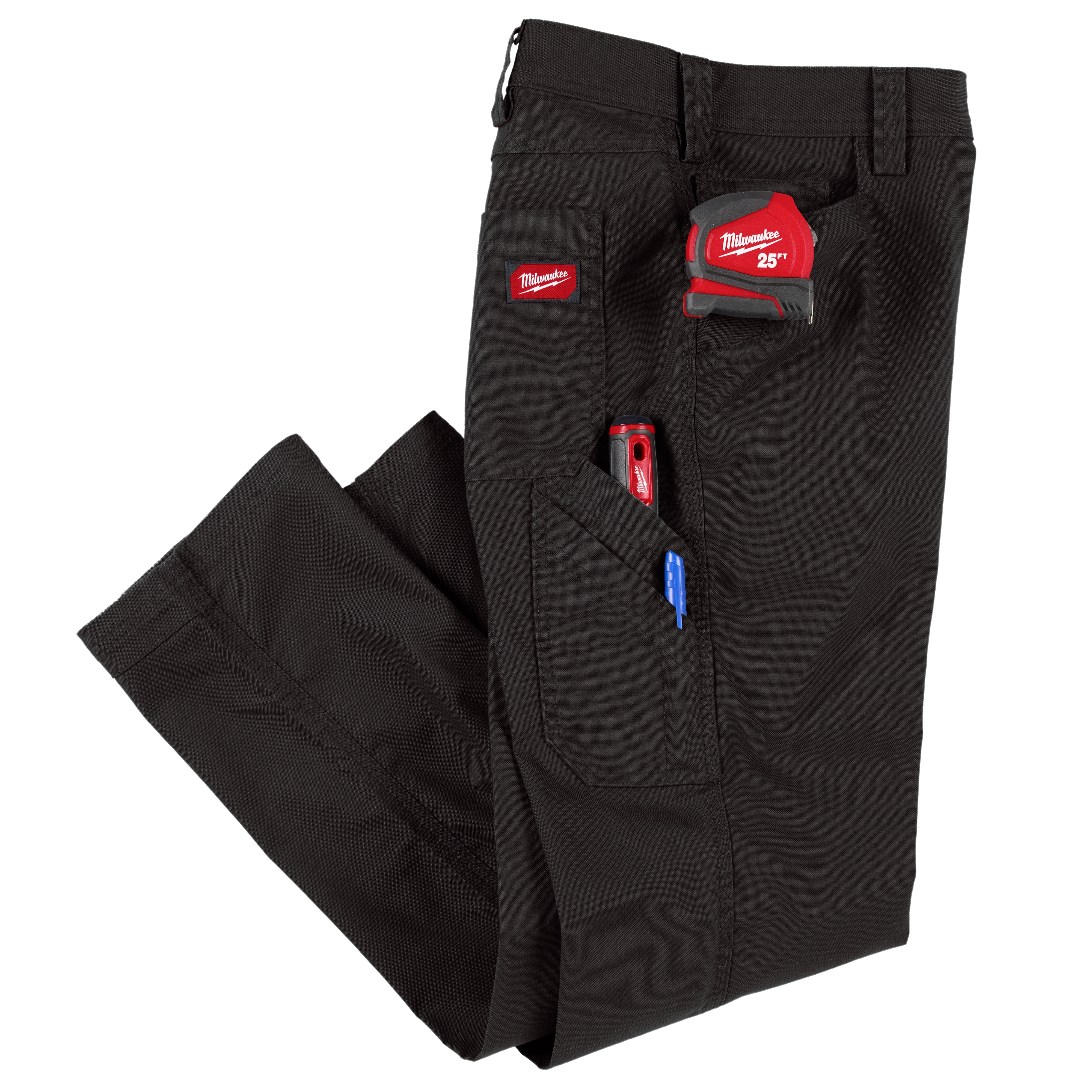 A pair of black work pants with multiple pockets. The pants have a Milwaukee 25-foot measuring tape, a red tool, and a blue pen visibly tucked into the pockets. There is a Milwaukee logo patch on one of the pockets.